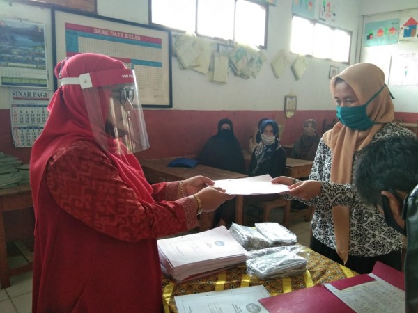 Pembagian rapot di SDN Ciranjang 1 Kecamatan Pasirjambu dilaksanakan pada ,Jumat (19/6). Nampa pada gambar seorang guru sedang membagikan buku rapot kepada orang tua sisa, dengan menarapkan standar protokol kesehatan.